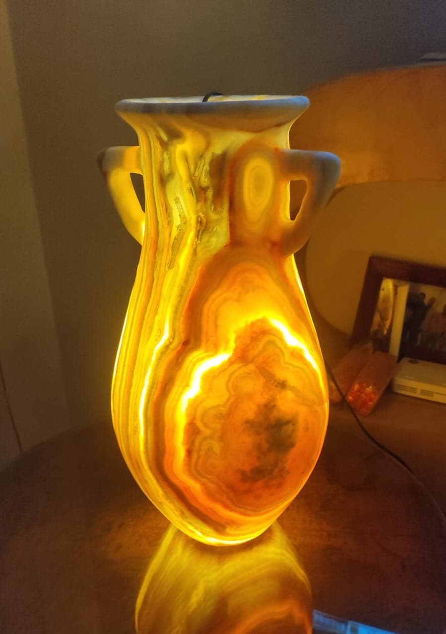 Twin-handled classical alabaster amphora vessel glowing with deep fiery golden light bands