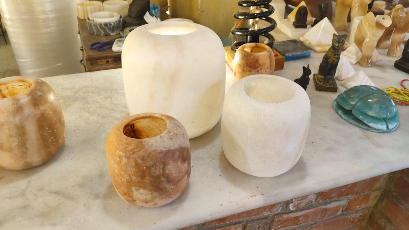 Modern thick-walled rounded cylindrical alabaster stone vessels on a workshop counter